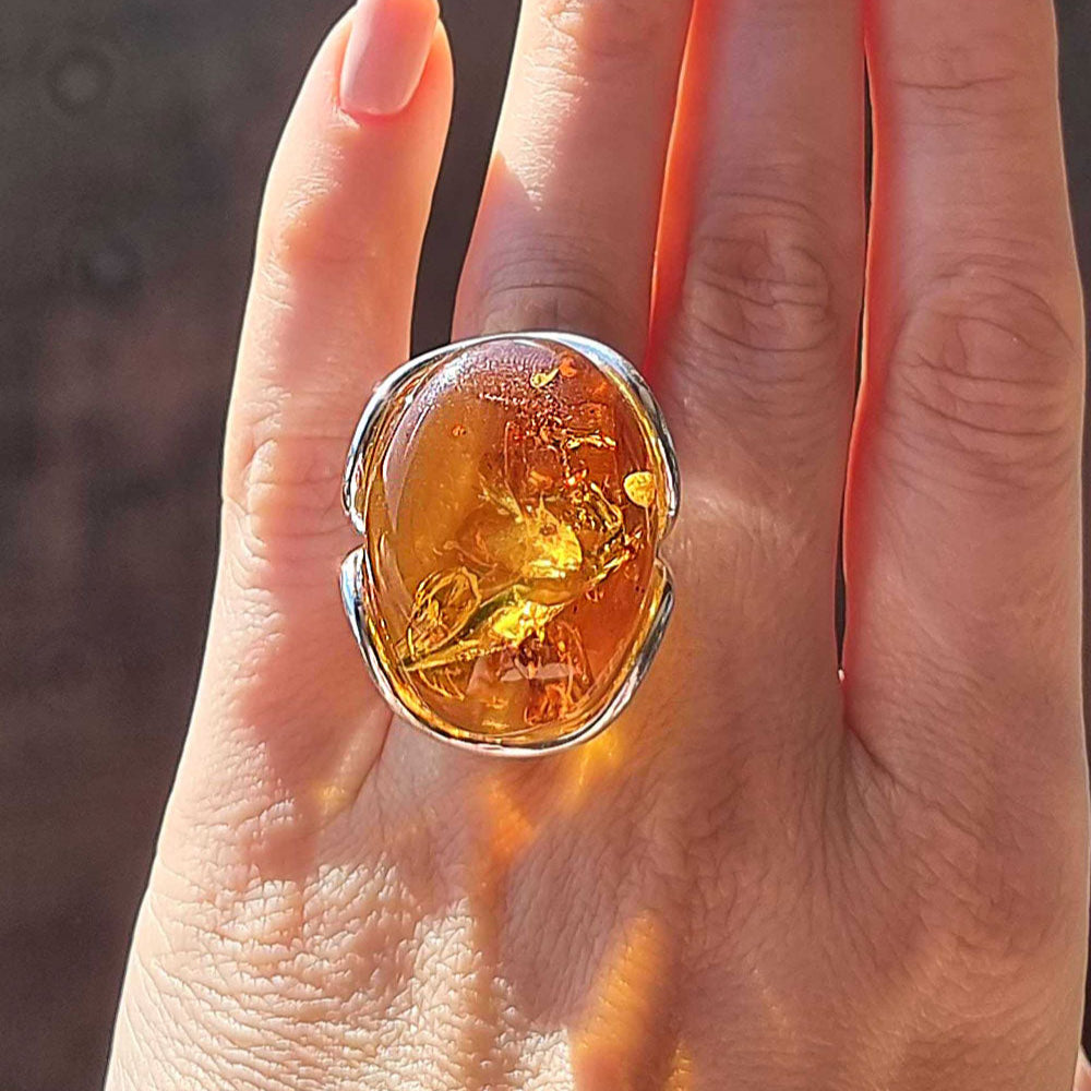 Ring with amber stone on a hand, brand 'Amber Alex' visible